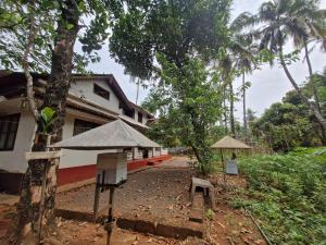 a building next to a tree with a bird house at Haris Farm House in Kannur