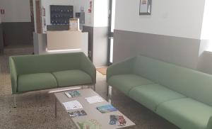 two green couches and a table in a room at Moderno Albergo Didattico in San Pellegrino Terme