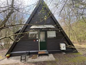 a black house with a green door in the woods at Chalet Séquoia 140, Durbuy nature, piscine,2 chiens Ok in Durbuy
