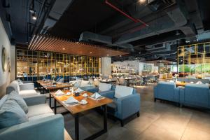 a restaurant with blue couches and tables and chairs at Grand Swiss-Belhotel Darmo in Surabaya