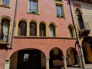 a red building with arches and windows on a street at Private Terrace Cozy Flat near Vicenza Center in Vicenza