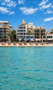 a beach with chairs and umbrellas in front of buildings at Hotel Marina Playa De Palma in El Arenal