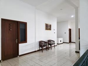 a hallway with two chairs and a table and a door at Casa Palma by Ezzego in Bandung