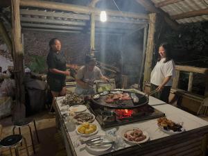 a group of people standing around a grill with food at Tanapavana閒雲居 in Alishan