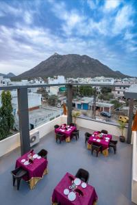 a balcony with tables and chairs and a mountain at The Parmatma Hotel in Udaipur