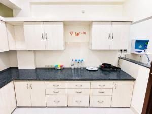 a kitchen with white cabinets and a black counter top at LaBelle Haven Aesthetic Cozy 2BHK For Family and Couples in Indore +14 photos