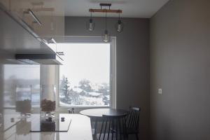 a kitchen with a table and a large window at Ludza Comfort Apartment in Ludza