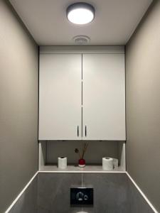 a bathroom with a white cabinet and two toilets at Ludza Comfort Apartment in Ludza