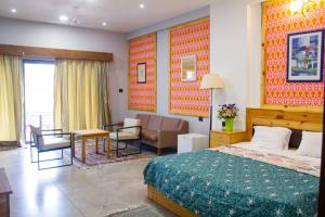 a bedroom with a bed and a living room at Shriji Ananda Hotel & Resort in Dhār