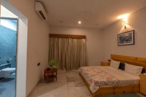 a bedroom with a bed and a bathroom with a sink at Shriji Ananda Hotel & Resort in Dhār
