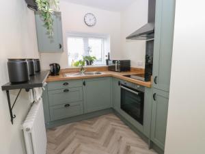 a kitchen with green cabinets and a sink and a window at 2 Low Road in Bishop Auckland