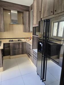 a kitchen with wooden cabinets and a black refrigerator at N24 Confy apartment in Luanda