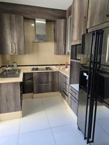 a kitchen with wooden cabinets and a black refrigerator at N24 Confy apartment in Luanda +9 photos