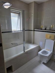 a bathroom with a tub and a toilet and a sink at N24 Confy apartment in Luanda