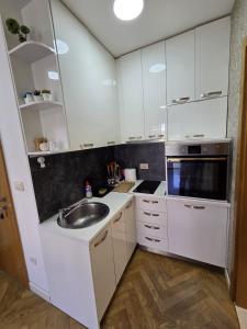 a kitchen with white cabinets and a sink at Luxury flat Boka Nest in Dobrota +5 photos