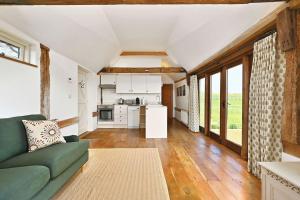 a living room with a green couch and a kitchen at Acorn Barn in Ashford +11 photos