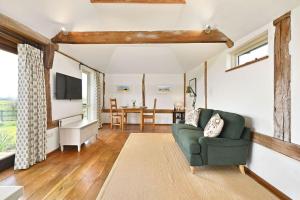 a living room with a green couch and a television at Acorn Barn in Ashford