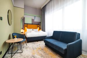 a bedroom with a bed and a couch and a chair at Focus Hotel Premium Olsztyn in Olsztyn
