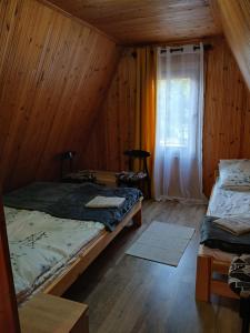 a attic room with two beds and a window at Domek nad jeziorem in Jagodne