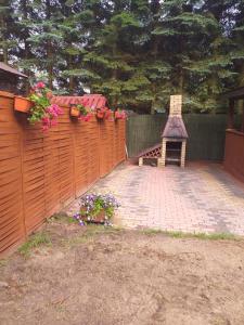 a backyard with a fence with a bench and flowers at Domek nad jeziorem in Jagodne +2 photos