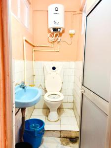 a small bathroom with a toilet and a sink at PEMA Hotel VSTM in Darjeeling