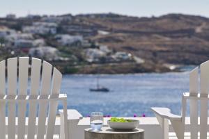 ein Tisch mit zwei Stühlen und einer Schüssel mit Futter und Wasser in der Unterkunft Pietra e Mare - Mykonos Moments by Mr and Mrs White in Kalo Livadi + 26 Fotos