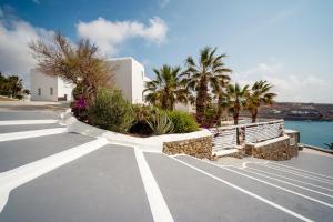 ein leerer Parkplatz mit Palmen und einem Gebäude in der Unterkunft Pietra e Mare - Mykonos Moments by Mr and Mrs White in Kalo Livadi
