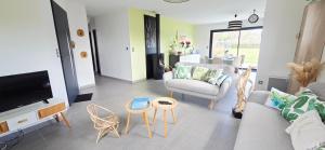 a living room with a couch and chairs and a tv at Fleur Du Ciel Vendée in Challans