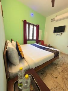 a bedroom with a bed in a room with green walls at Naadi Grand Inn in Thanjāvūr