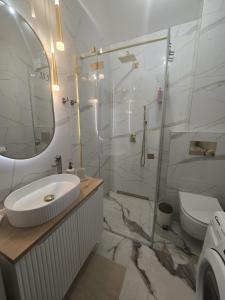 a white bathroom with a sink and a shower at Apartament Sosnowy Las Widok na morze in Rowy +23 photos