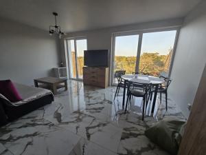 a living room with a marble floor and a table at Apartament Sosnowy Las Widok na morze in Rowy