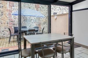 a patio with tables and chairs and an umbrella at Maison charmante près de Sainte Catherine in Honfleur