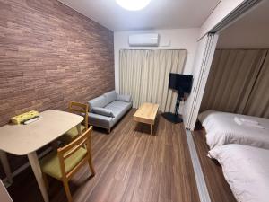 ein Hotelzimmer mit einem Bett, einem Tisch und einer Couch in der Unterkunft casa de sol in Miyakojima