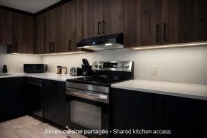 a kitchen with black cabinets and a stove top oven at Room with 2 Queen-Size Beds Downtown Quebec in Quebec City