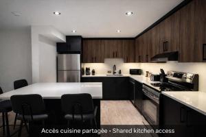 a kitchen with black cabinets and a white counter top at Room with 2 Queen-Size Beds Downtown Quebec in Quebec City