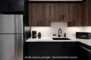 a kitchen with wooden cabinets and a stainless steel refrigerator at Room with 2 Queen-Size Beds Downtown Quebec in Quebec City
