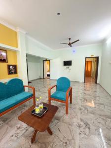a living room with two blue chairs and a table at Naadi Grand Inn in Thanjāvūr