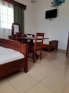 a room with a table and chairs and a television at RAOOF HOTEL in Mahajanga