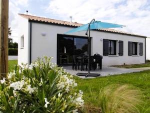 a house with a table and a blue umbrella at Fleur Du Ciel Vendée in Challans