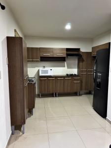 a kitchen with wooden cabinets and a black refrigerator at Casa en Privada! in Culiacán