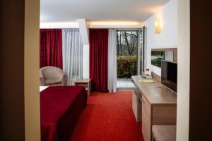 a hotel room with a bed and a desk and a television at Hotel Herastrau in Bucharest