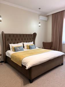a bedroom with a large bed with a large headboard at Keremet Hotel in Almaty