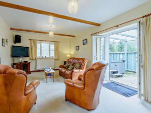 a living room with leather furniture and a sliding glass door at 3 Bed in Builth Wells oc-52463 in Alltmawr