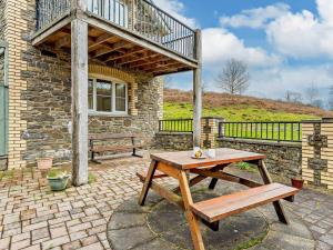 a wooden table and bench on a brick patio at 3 Bed in Builth Wells oc-52463 in Alltmawr