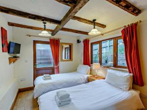 two beds in a room with red curtains at 3 Bed in Bridgnorth oc-therr in Shrewsbury