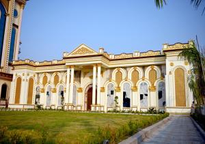 a large yellow building with a palm tree in front at Solenne Retreat in Bodh Gaya