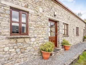 a stone house with two potted plants in front of it at 4 Bed in Llandovery oc-82440 in Llanfair-ar-y-bryn