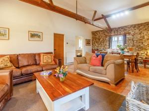 a living room with leather furniture and a stone wall at 3 Bed in Abergavenny oc-90233 in Llanvetherine