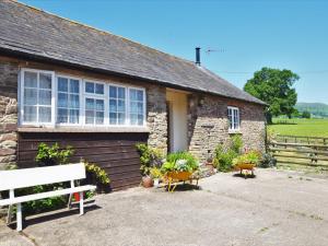 a brick house with a white bench in front of it at 3 Bed in Abergavenny oc-90233 in Llanvetherine