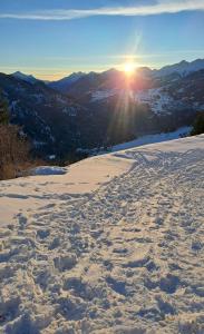 a snow covered slope with the sun in the distance at Hof am Berg in Kaunerberg +2 photos